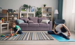 a woman and a child playing on a rug in a living room
