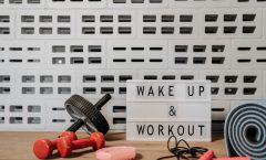 Fitness gear and motivational sign in home gym setup against a brick wall.